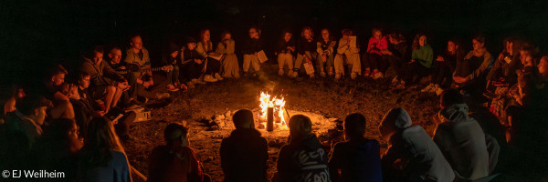 Konfis sitzen um ein Lagerfeuer